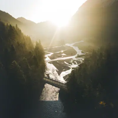 Garmisch Landschaft Eine Brücke über einen Fluss, umgeben von Bäumen.