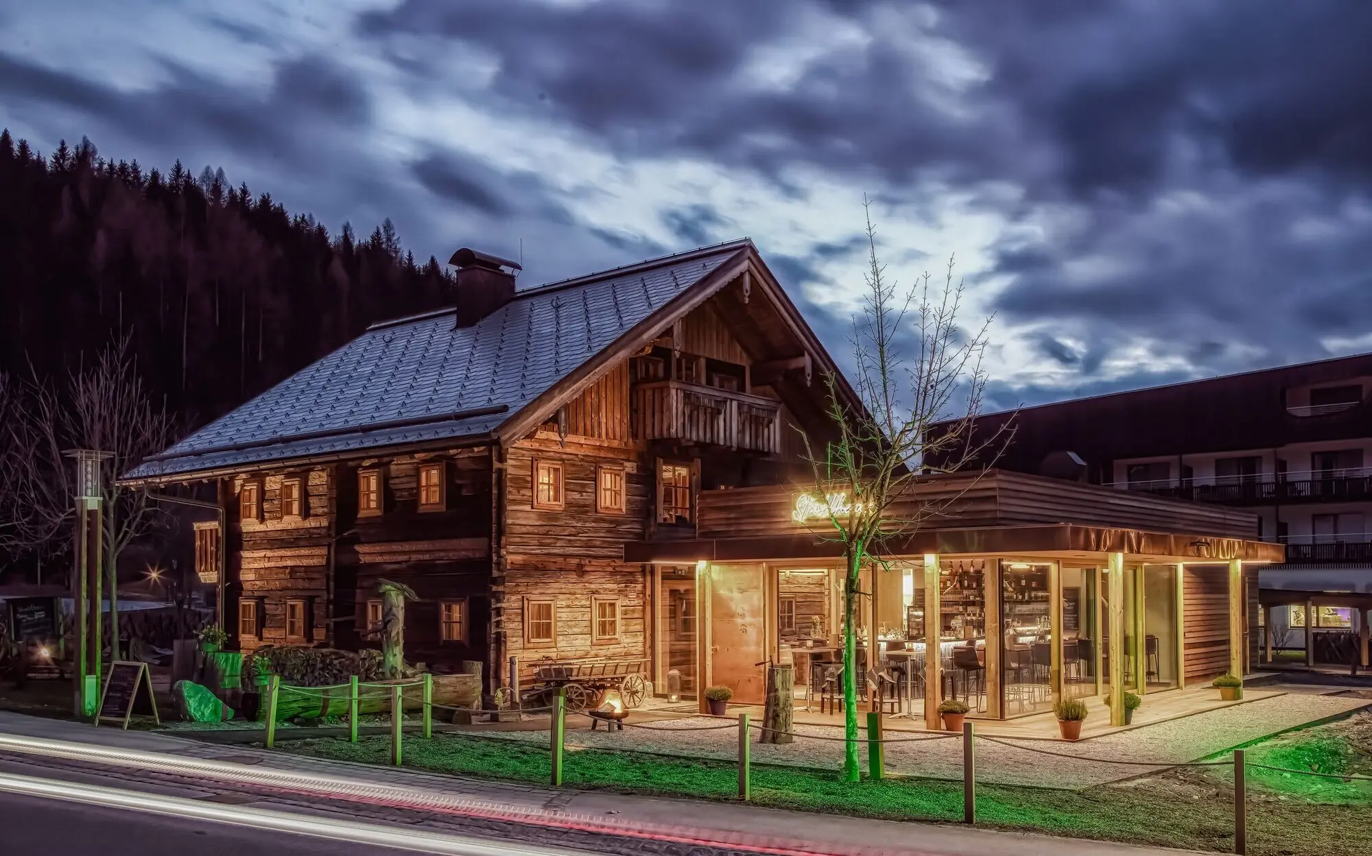 Ein uriges Holzhaus mit warmer Beleuchtung bei Dämmerung.