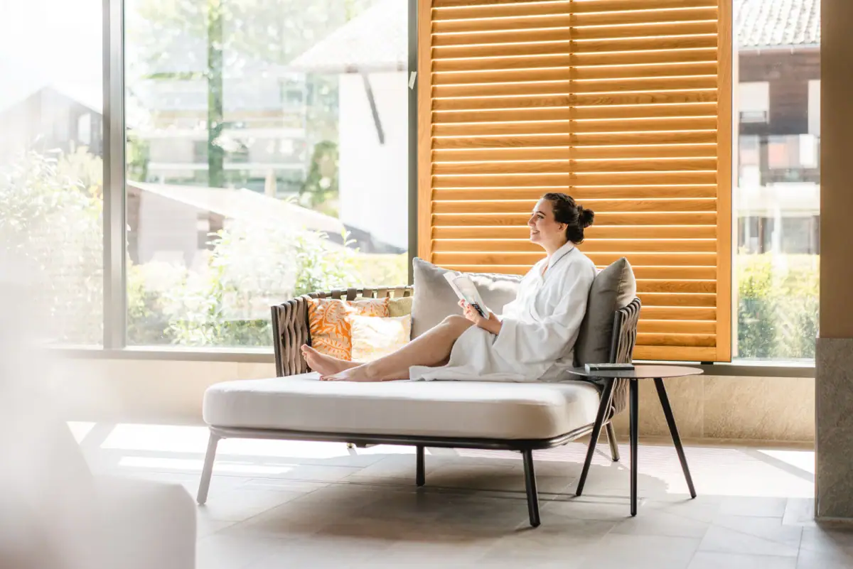 SPA-Liege Eine Frau in einem weißen Bademantel sitzt auf einem Sofa.