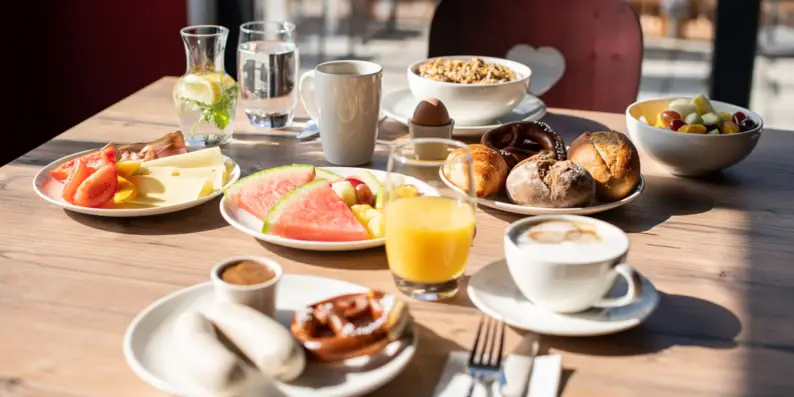 Frühstückstisch gedeckt mit Früchten, Brötchen und Getränken in angenehmer Atmosphäre. Frühstückstisch gedeckt mit Früchten, Brötchen und Getränken in angenehmer Atmosphäre.