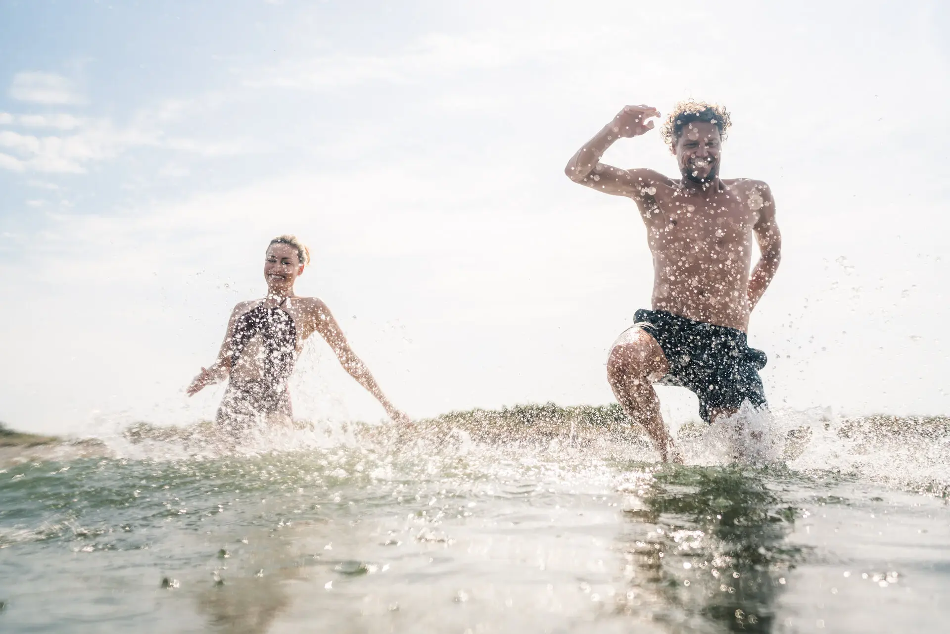 Baden im Meer Zwei Personen laufen im Wasser am Strand.