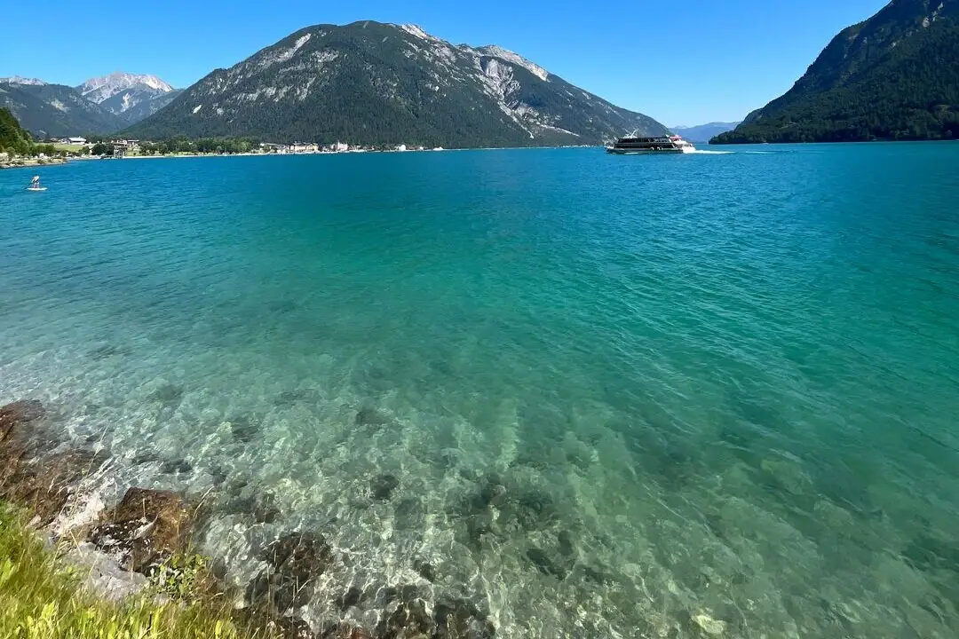 Achensee Ein Gewässer mit Bergen im Hintergrund.