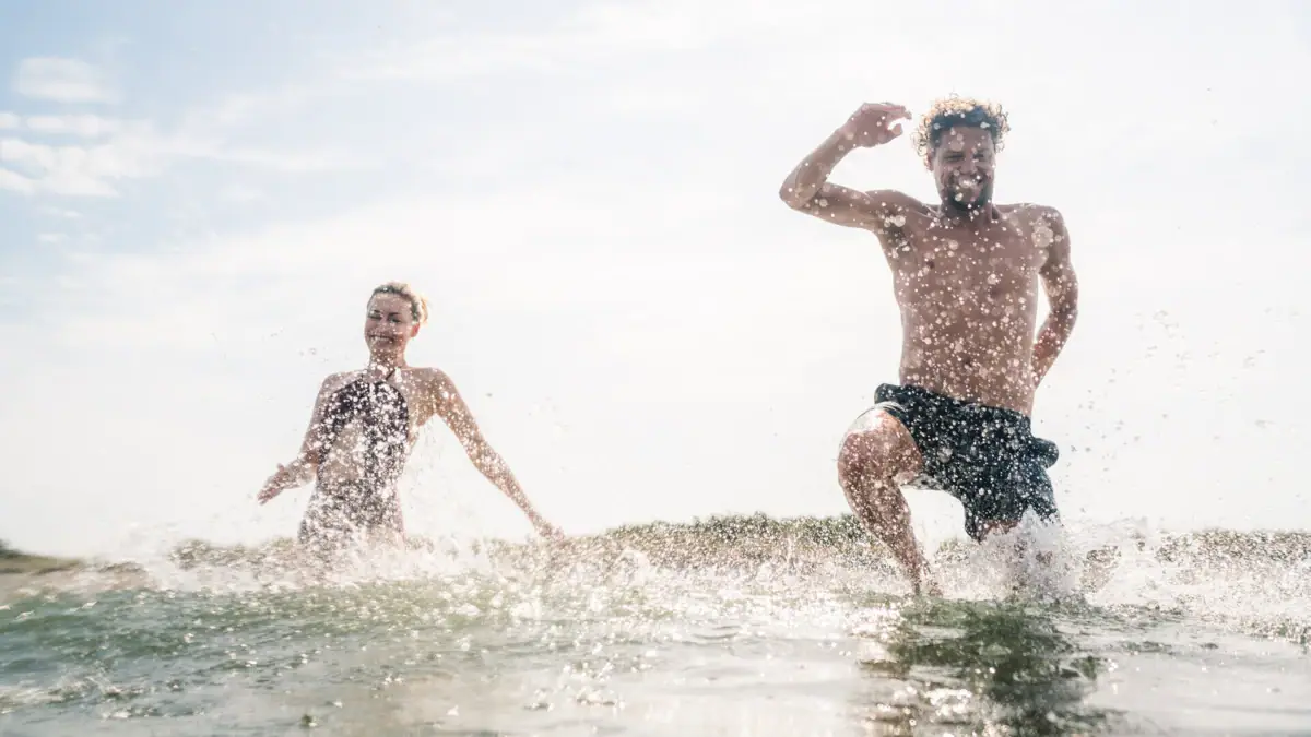 Anbaden Zwei Personen laufen im Wasser.