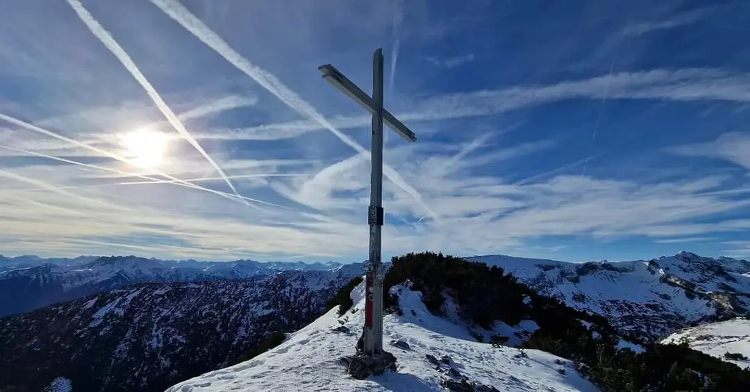 Kreuz auf einem verschneiten Berggipfel.