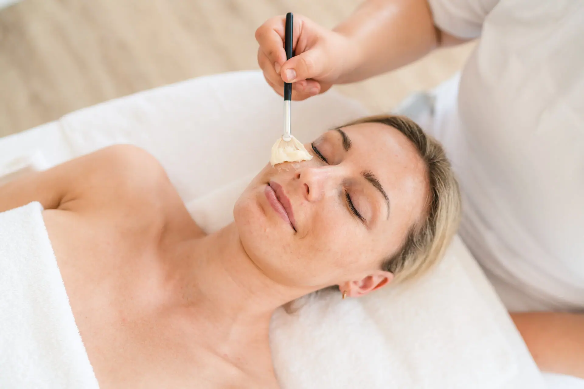 Gesichtsanwendung Eine Frau liegt mit einem Pinsel auf ihrem Gesicht.