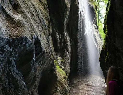 Schlucht Eine Frau steht in einer Höhle mit einem Wasserfall.