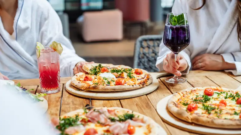 Pizza in der Poolbar Eine Gruppe von Menschen sitzt an einem Tisch mit Pizzen und Getränken.