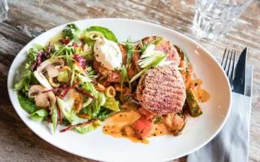 Ein Essensteller mit Salat, Fleisch und gekochtem Gemüse.