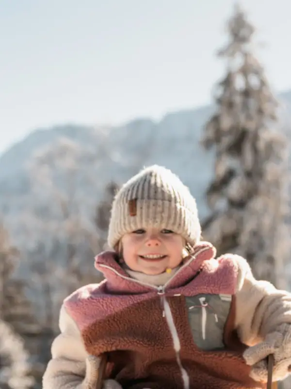 Kind im Schnee Ein Kind sitzt auf einem Schlitten im Schnee.