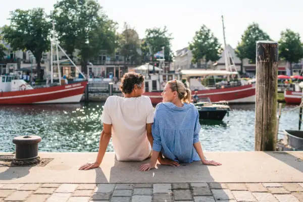 Alter Strom Ein Mann und eine Frau sitzen auf einem Vorsprung und schauen sich an.