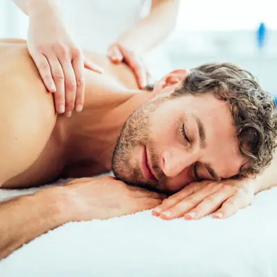 Massage Ein Mann liegt auf einer weißen Fläche.