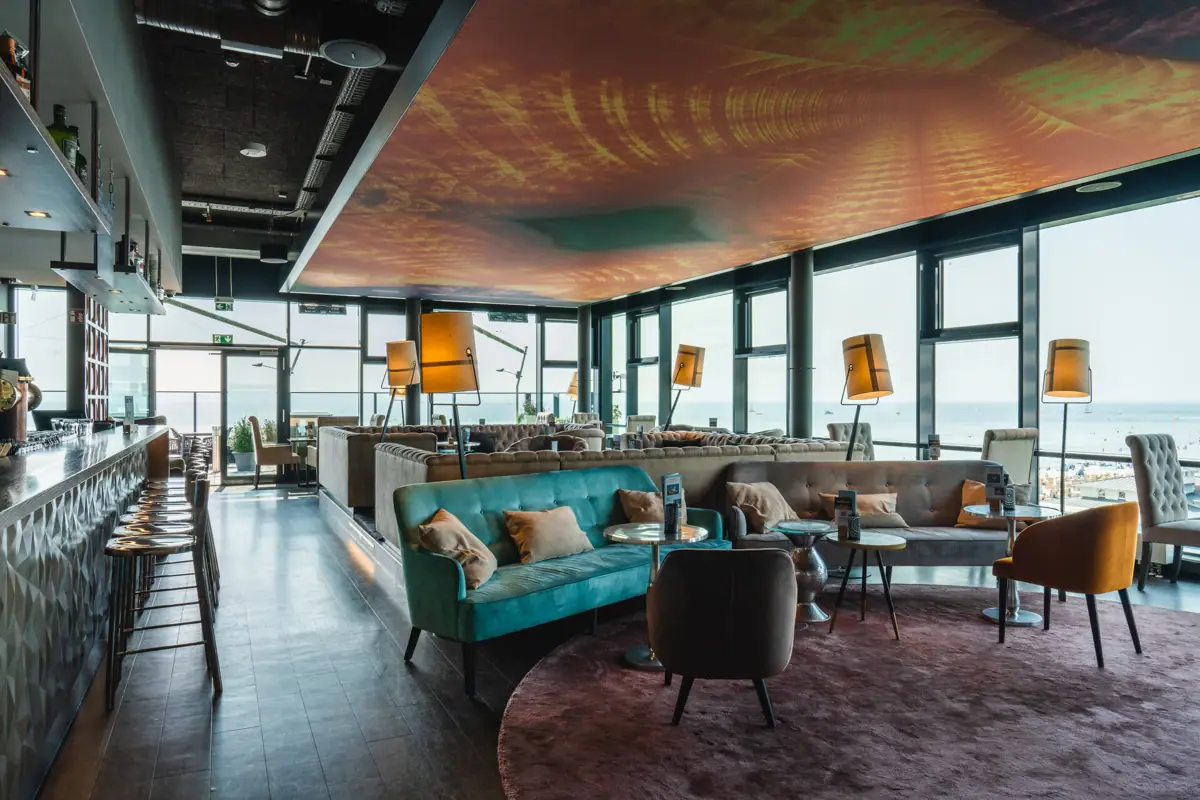 Bar im aja Grömitz Ein Raum mit einem großen Fenster und einer Couch.