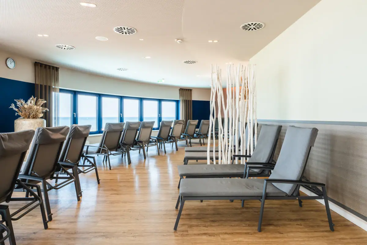 Ruhebereich im aja Warnemünde Ein Raum mit Liegen und Fenstern.