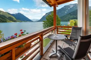 Balkon Ein Balkon mit Tisch und Stühlen mit Blick auf einen See.