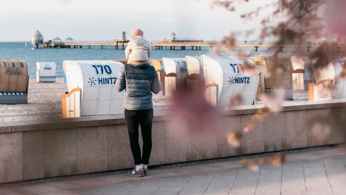 Promenade Grömitz Ein Mann steht auf einer Promenade mit einem Baby auf ihren Schultern.