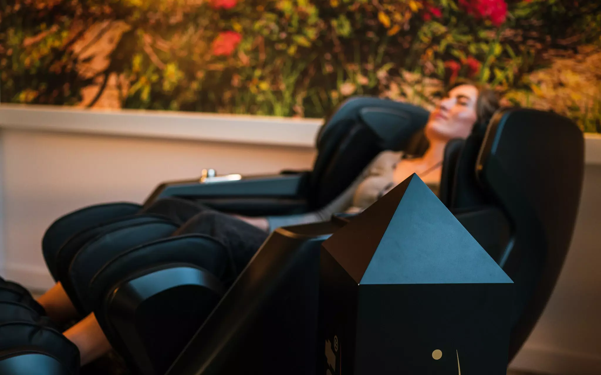 Massage-Sessel Eine Frau entspannt sich in einem modernen Massagesessel, umgeben von einer beruhigenden, natürlichen Atmosphäre.