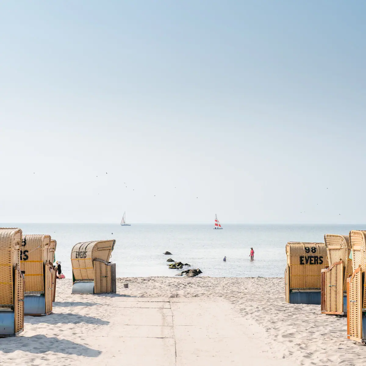 Strandaufgang Ein Strand mit vielen Körben und einem Gewässer.