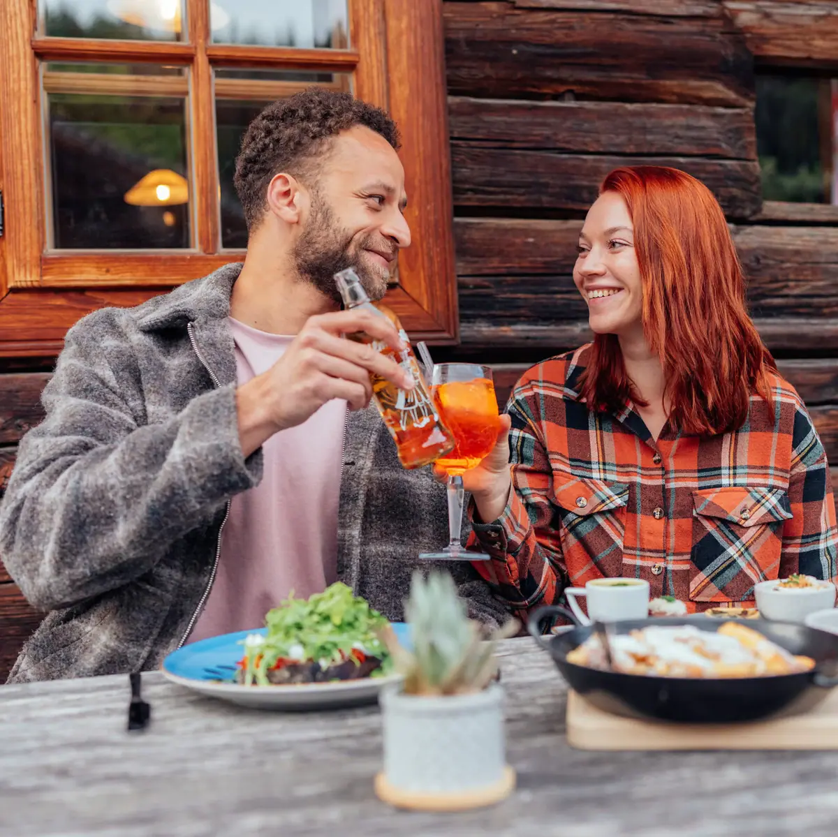 Essen im Stroblhaus Ein Mann und eine Frau trinken an einem Tisch mit Essen und einer Pfanne.