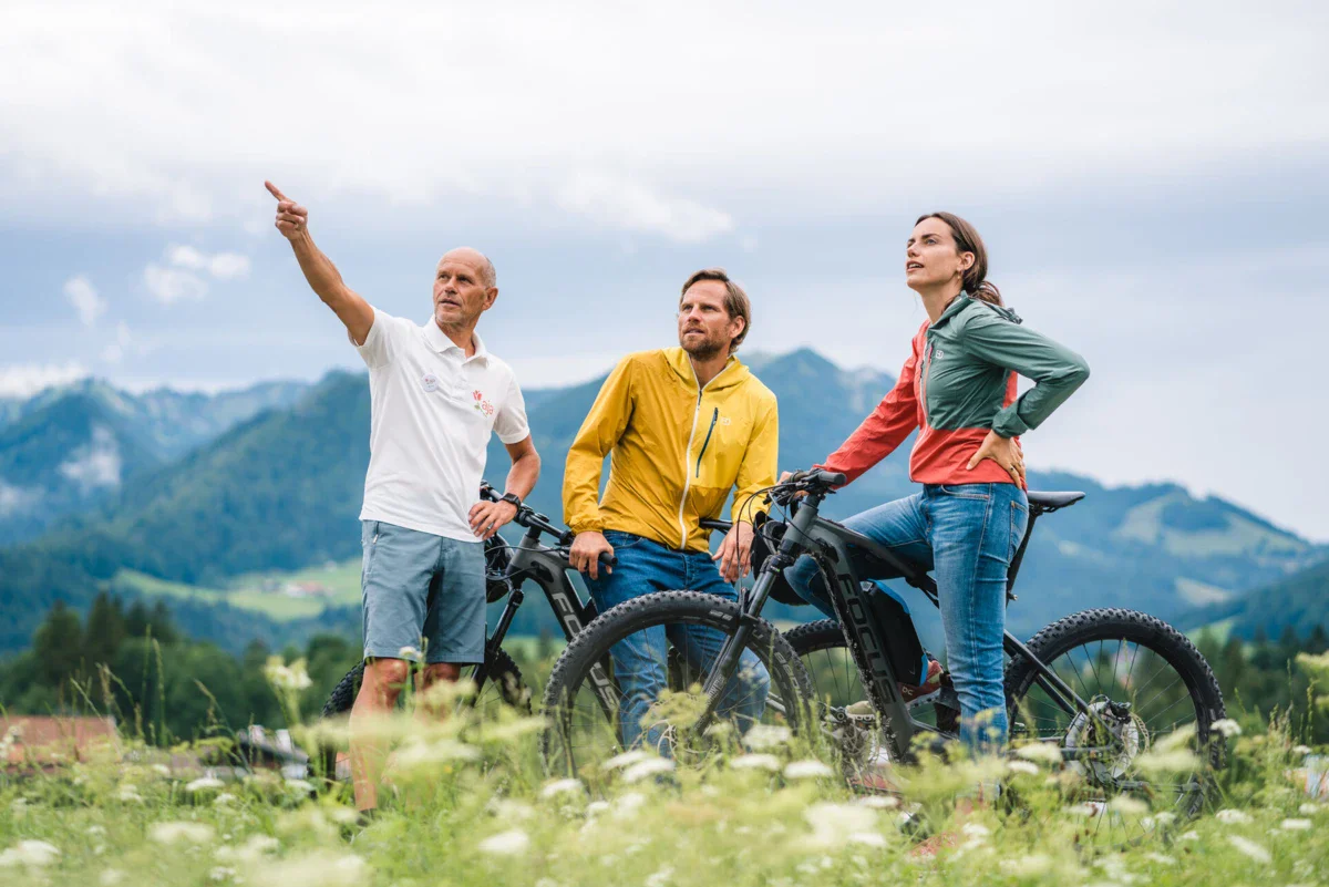 E-Bike Tour Eine Gruppe von Menschen steht mit Fahrrädern auf einem Feld.