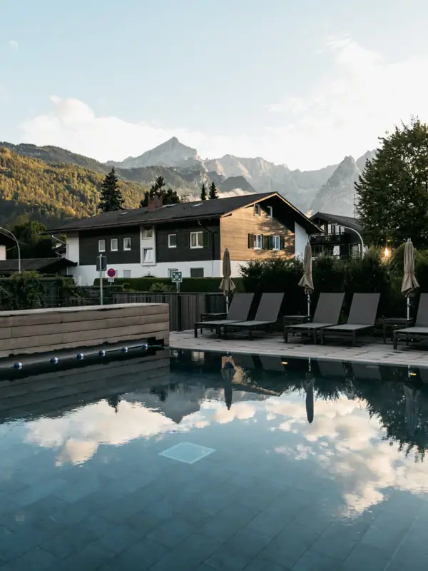 Außenpool Ein Pool mit Stühlen und einem Gebäude im Hintergrund.