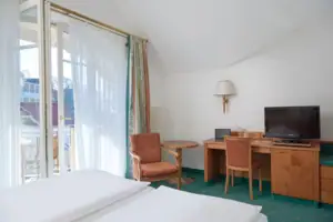 Doppelzimmer landseitig mit Balkon Ein Raum mit einem Schreibtisch, Stühlen und einem Computer.