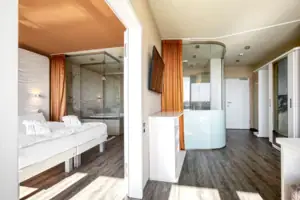 Suite im aja Warnemünde Ein Zimmer mit einem Bett und einer Dusche.