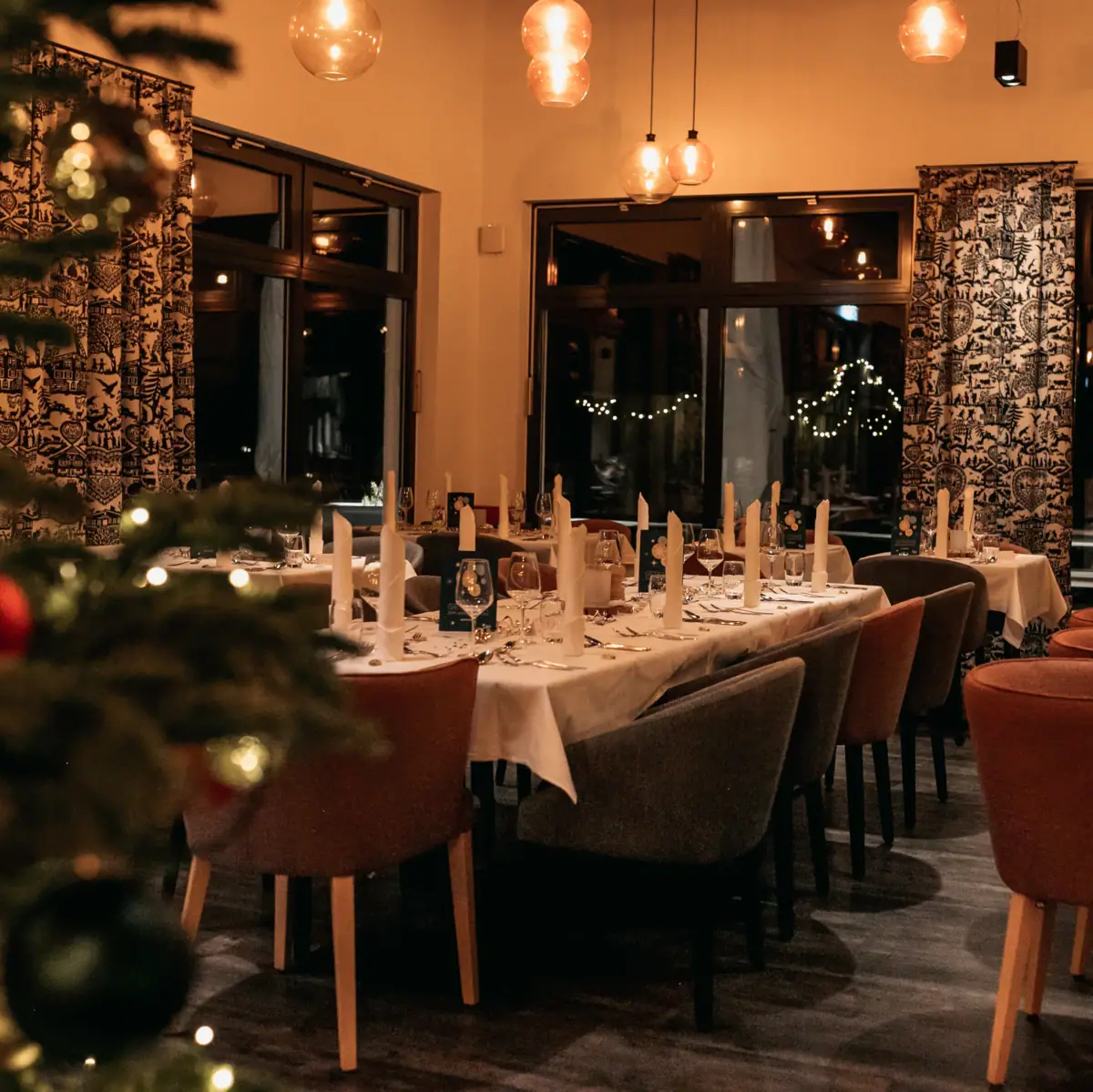 Festliches Restaurant Ein Raum mit Tischen und Stühlen, ein Weihnachtsbaum steht im Hintergrund.