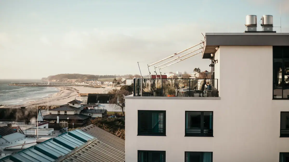 aja Grömitz Ein Gebäude mit einem Balkon, der auf ein Gewässer blickt.