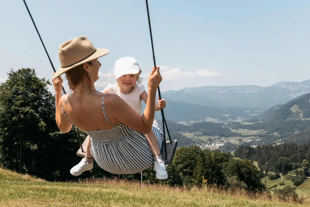 Schaukeln Eine Frau und ein Kind schaukeln im Freien.