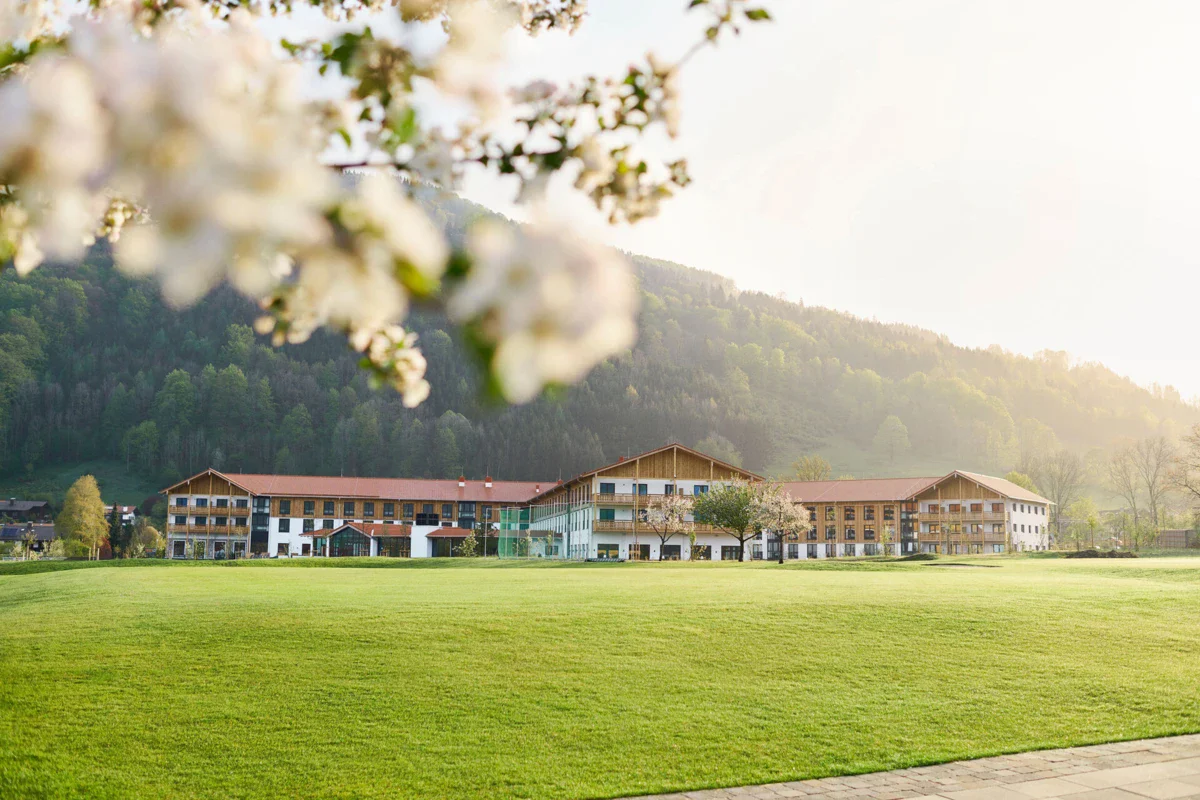 aja Ruhpolding vom Golfplatz aus Ein Golfplatz in Ruhpolding mit Gebäuden im Hintergrund.