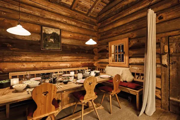 Ein uriger Gastraum mit einem Tisch und Stühlen.