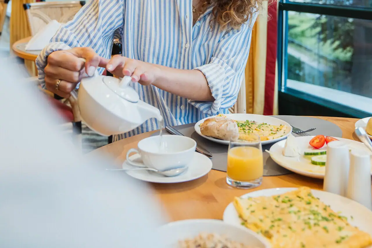 Tee Eine Frau gießt Tee in eine Tasse ein.