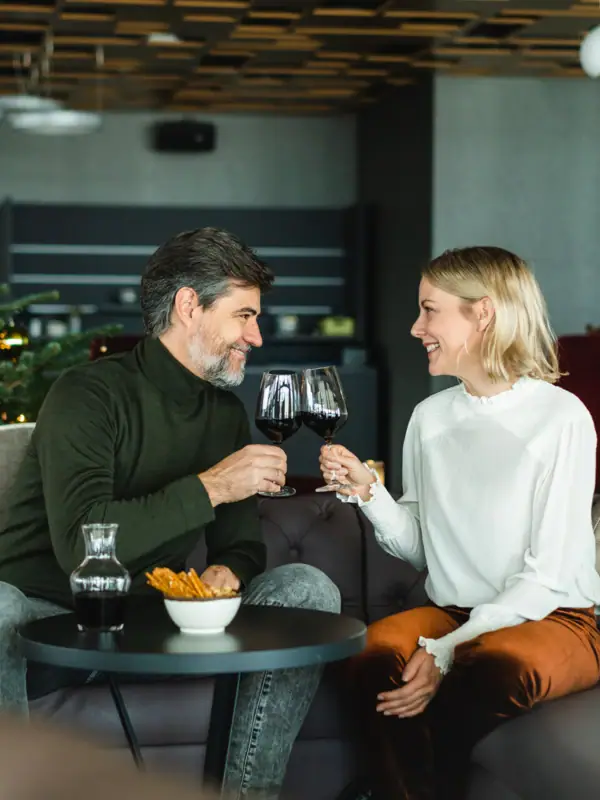 Bar mit Tannenbaum Ein Mann und eine Frau sitzen auf einem Sofa und trinken Wein.
