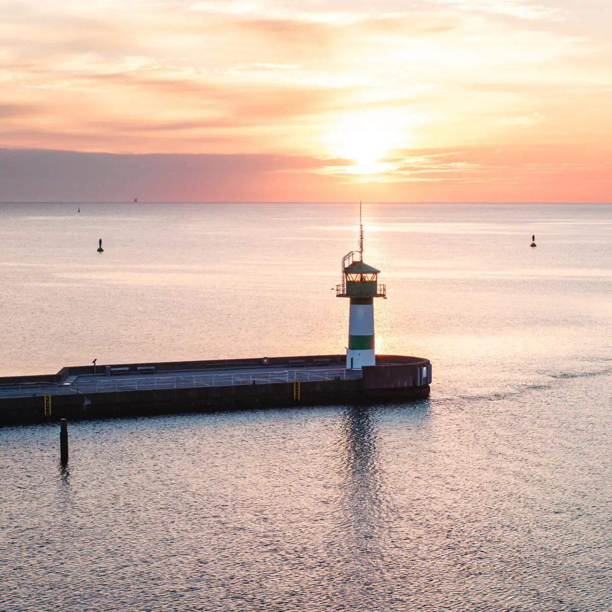 Molenfeuer Die grün weiße Nordermole mit dem Wasser bei Sonnenaufgang.
