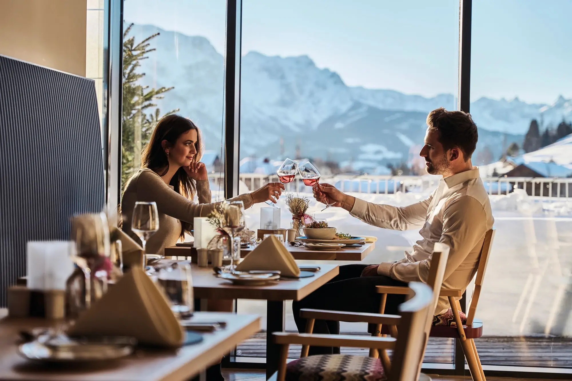 Restaurant Feinspitz Ein Mann und eine Frau sitzen an einem Tisch im Freien und halten Weingläser.