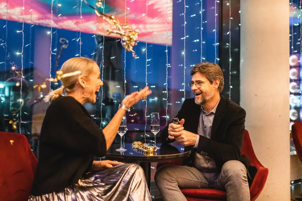 Silvester im aja Travemünde Ein Mann und eine Frau sitzen an einem Tisch mit Weingläsern.