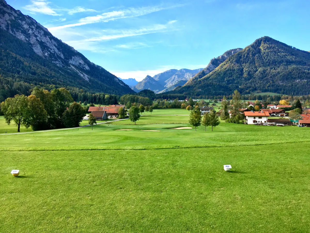 Golfplatz in Ruhpolding Ein Golfplatz in Ruhpolding mit Bäumen und Bergen im Hintergrund.