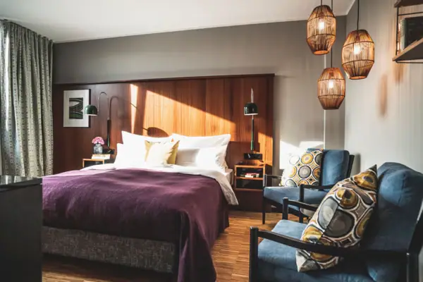 Zimmer HENRI Düsseldorf Ein Schlafzimmer mit einem Bett und Stühlen.