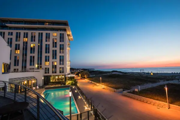 Wellnesshotel aja Warnemünde Das Hotel mit dem Außenpool und einem Gehweg entlang der Ostsee.