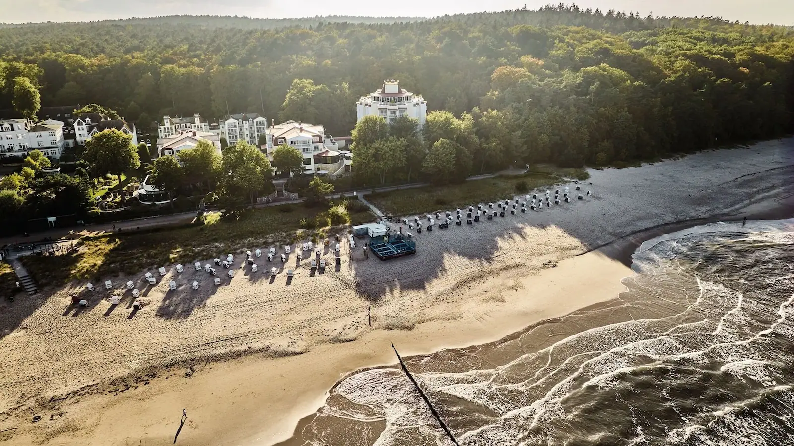 aja Strandhotel Bansin Ein Strand mit vielen Strankörben und Bäumen.