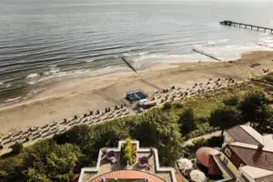 aja Strandhotel Bansin Strand mit Strankörben und Bäumen am Ufer.
