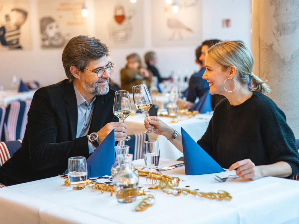Silvester im aja Travemünde Ein Mann und eine Frau sitzen an einem Tisch mit Weingläsern.
