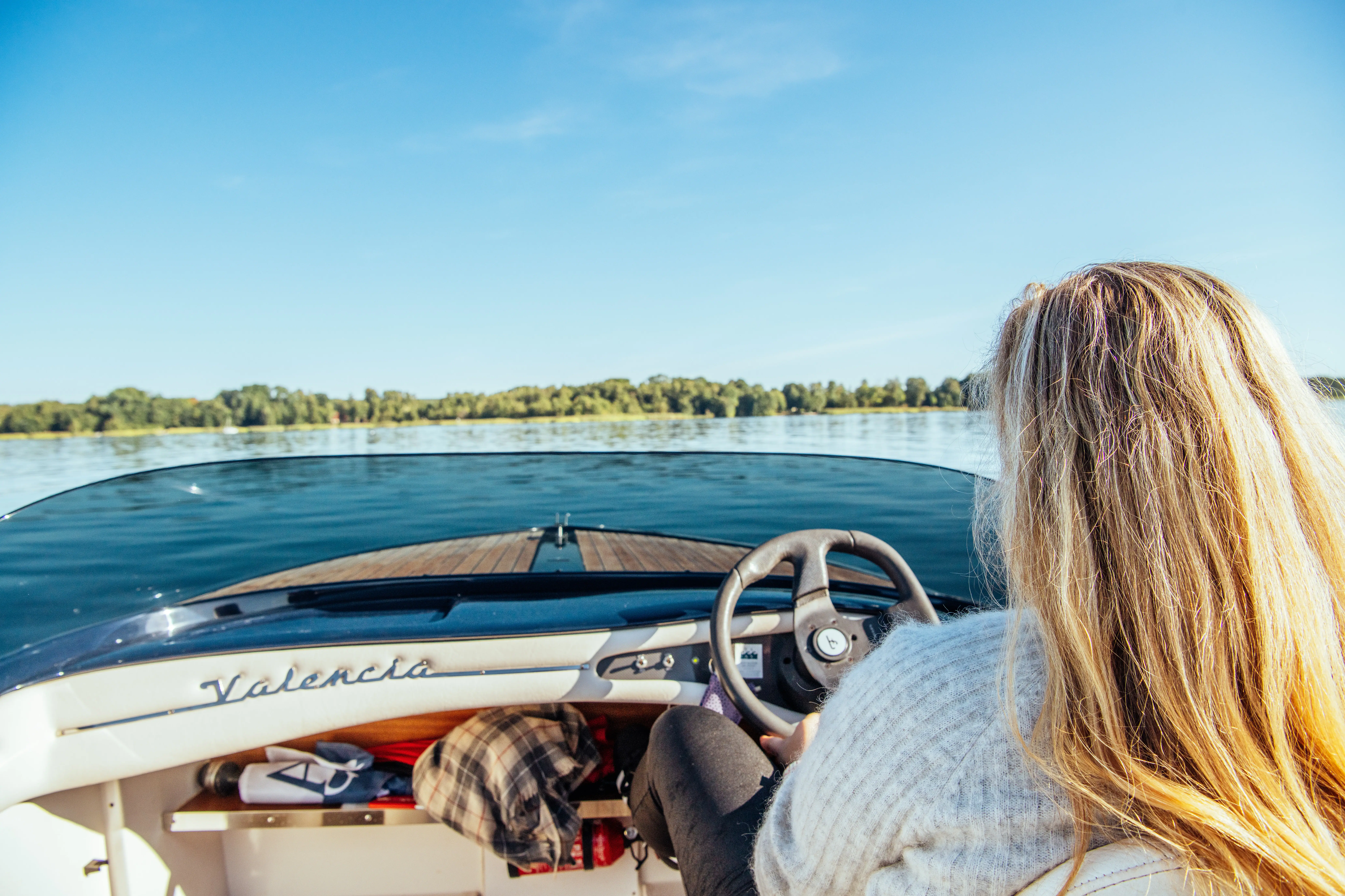 Eine Frau sitzt in einem E-Boot und steuert über den See.