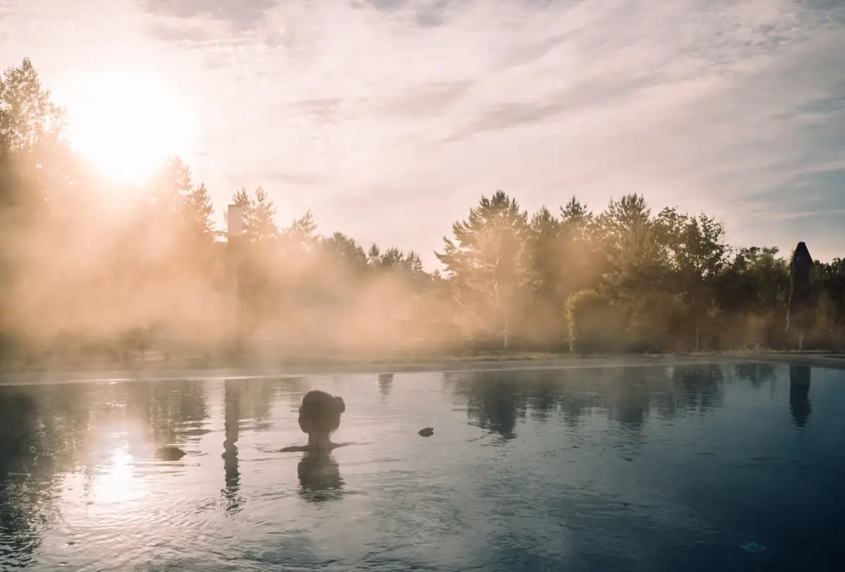 Day SPA im aja Bad Saarow Eine Person im Wasser, umgeben von Bäumen in einer natürlichen Umgebung.