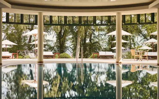 Ein Pool mit Sonnenschirmen und Stühlen im Hintergrund. Ein Pool mit Sonnenschirmen und Stühlen im Hintergrund.