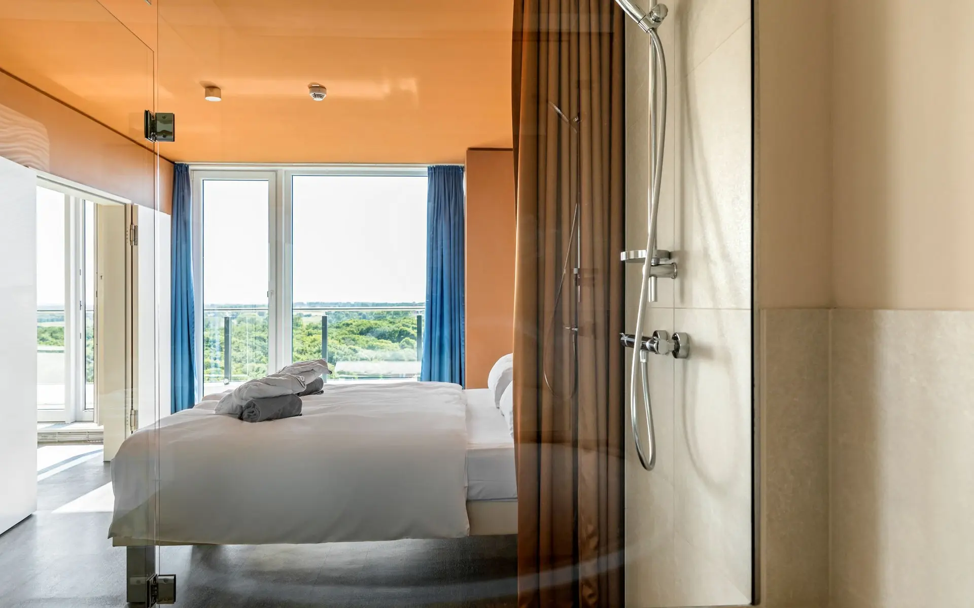 Ein Zimmer mit Bett und im Vordergrund ist die Dusche