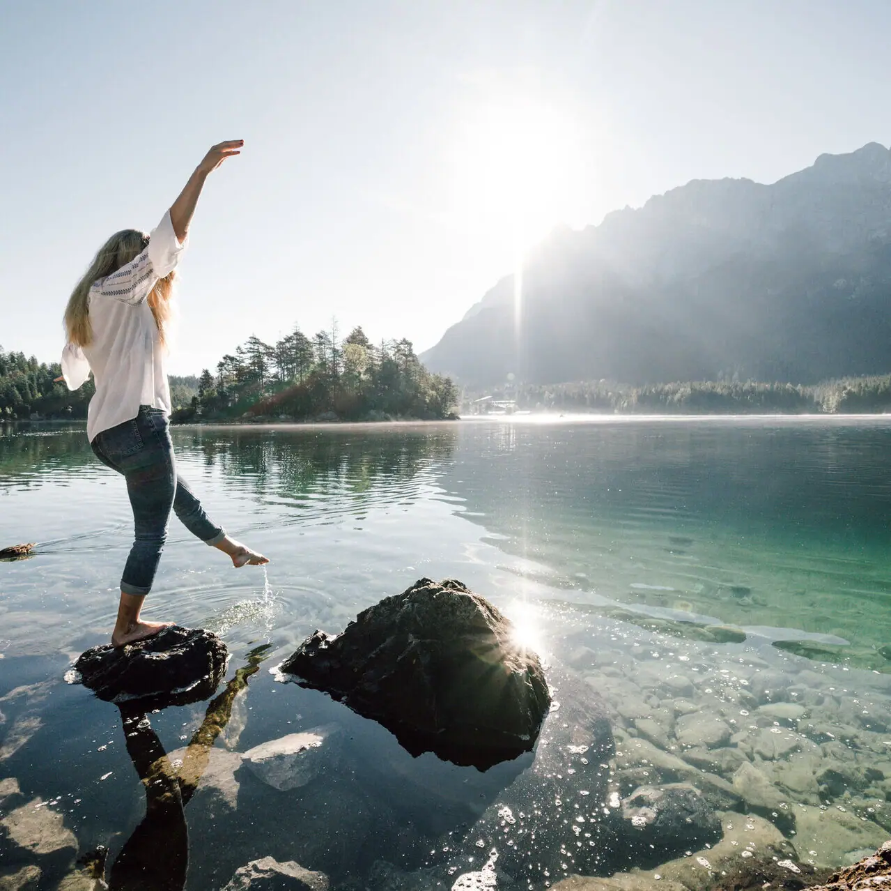 Eibsee Ene Frau balanciert auf einem Stein am Eibsee in Garmisch-Partenkirchen.