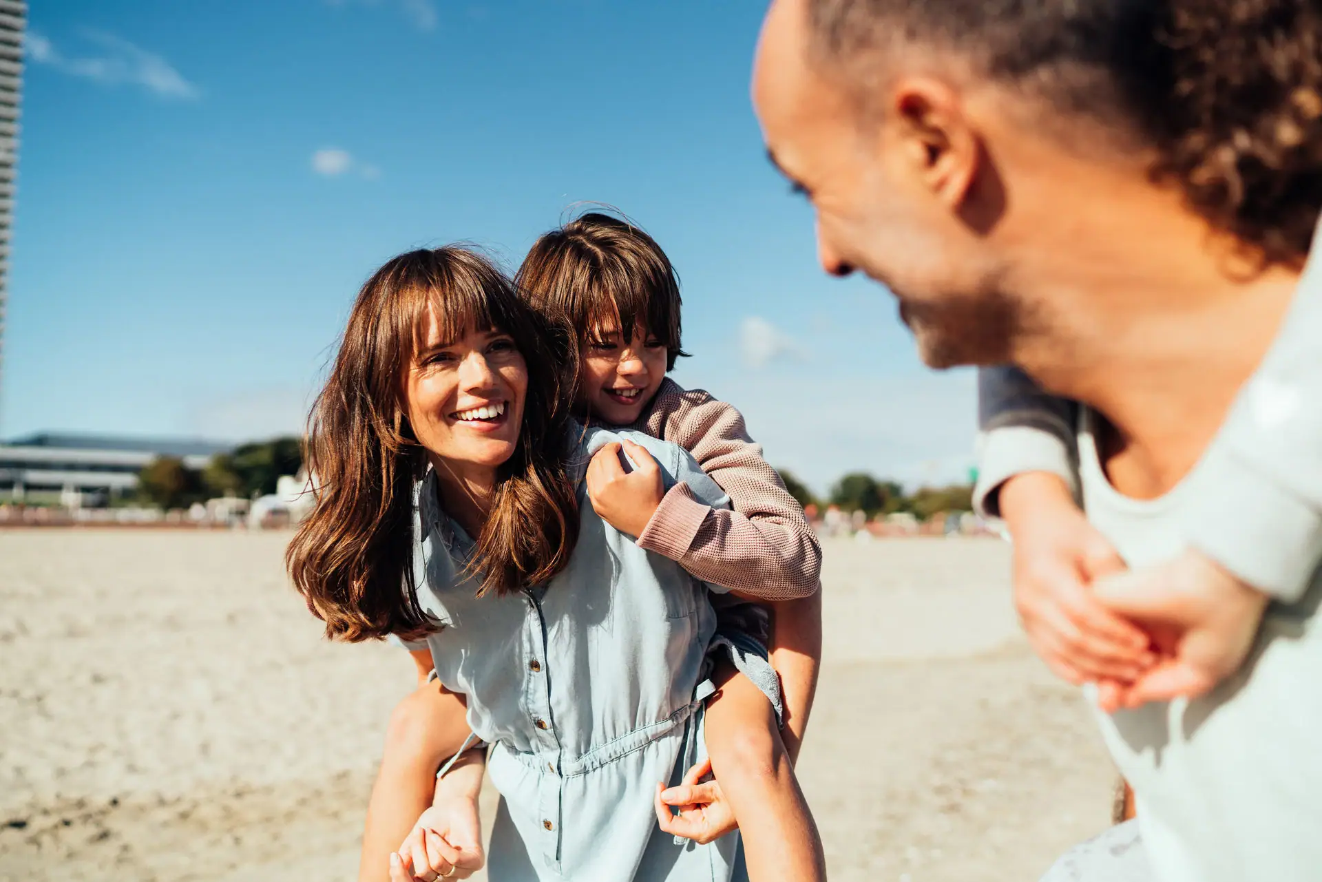 Familienurlaub bei aja Ein Mann und eine Frau halten ein Kind am Strand.