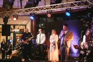 Live Musik Eine Gruppe von Menschen auf einer Bühne bei einem Konzert mit Musikinstrumenten.