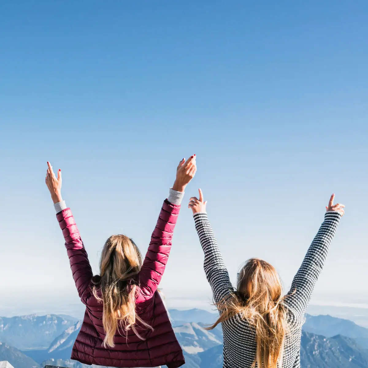 Ausblick Zugspitze Zwei Frauen stehen auf einem Berg mit erhobenen Armen.